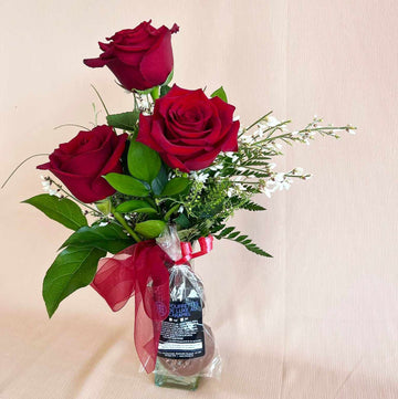 Arrangement dans un vase avec roses rouges + chocolats.