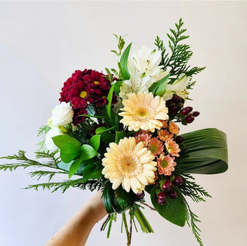 Emballage teintes de blanc, bourgogne et pêche avec verdure hivernale.